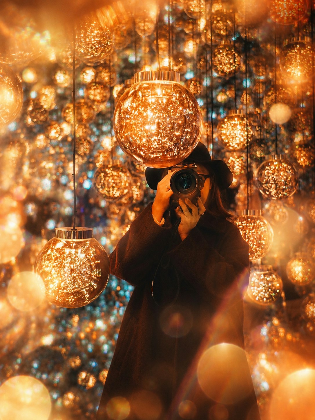 手にカメラを持つ人物ときらめくクリスマス風の電飾