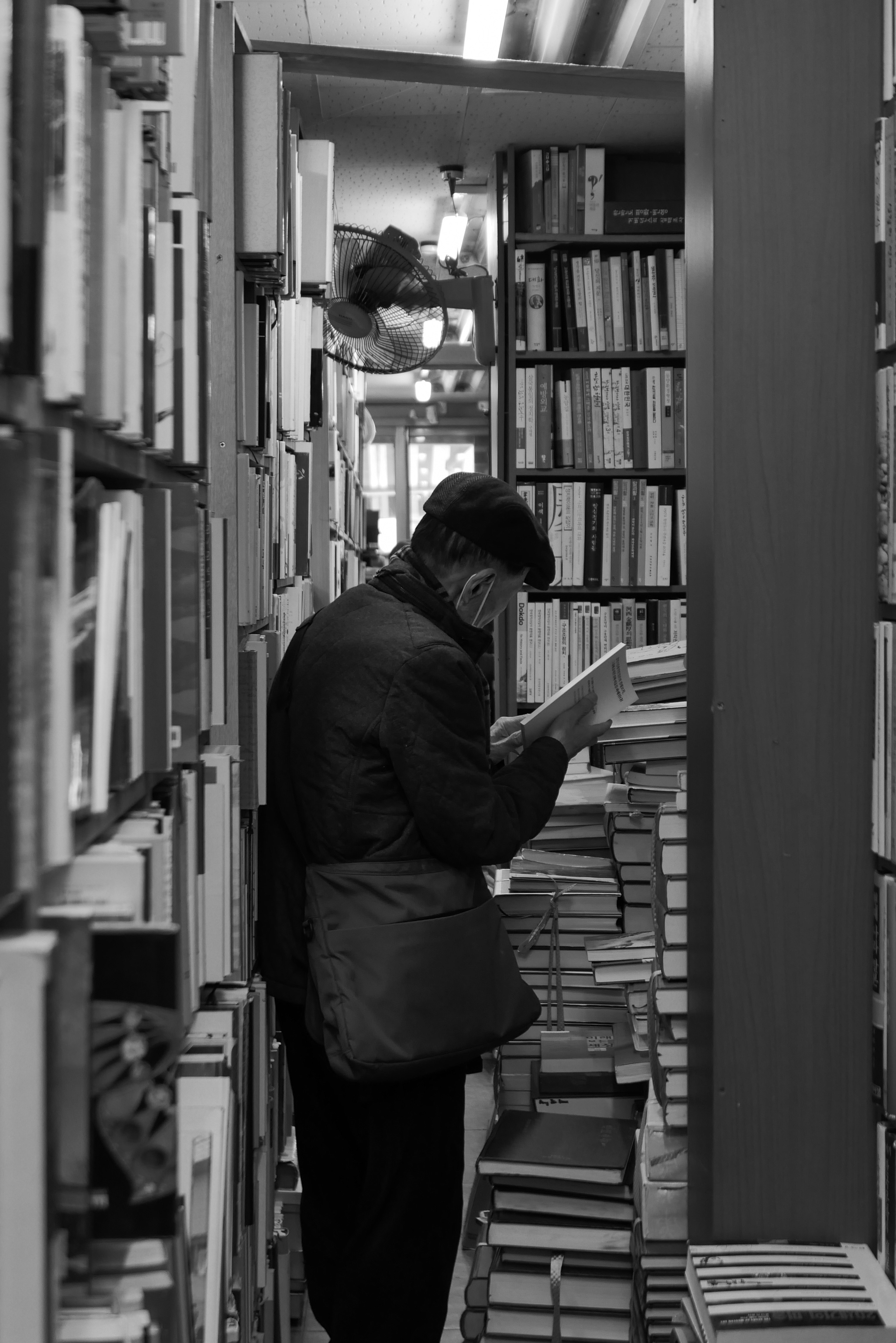 本棚の間で本を読む人の姿