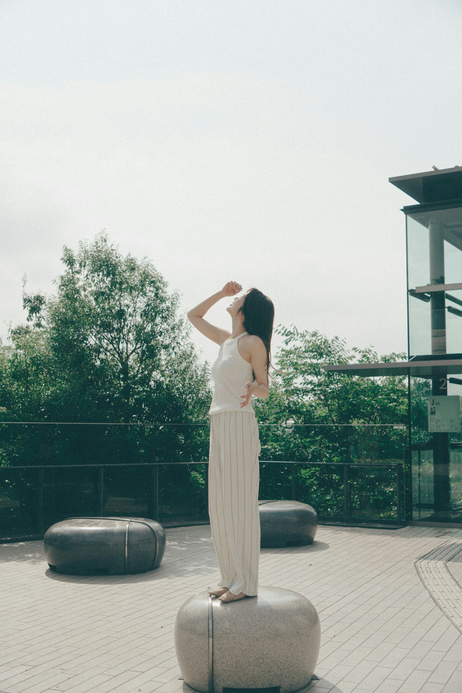 Một người phụ nữ đứng trên một viên đá ngoài trời nhìn lên bầu trời