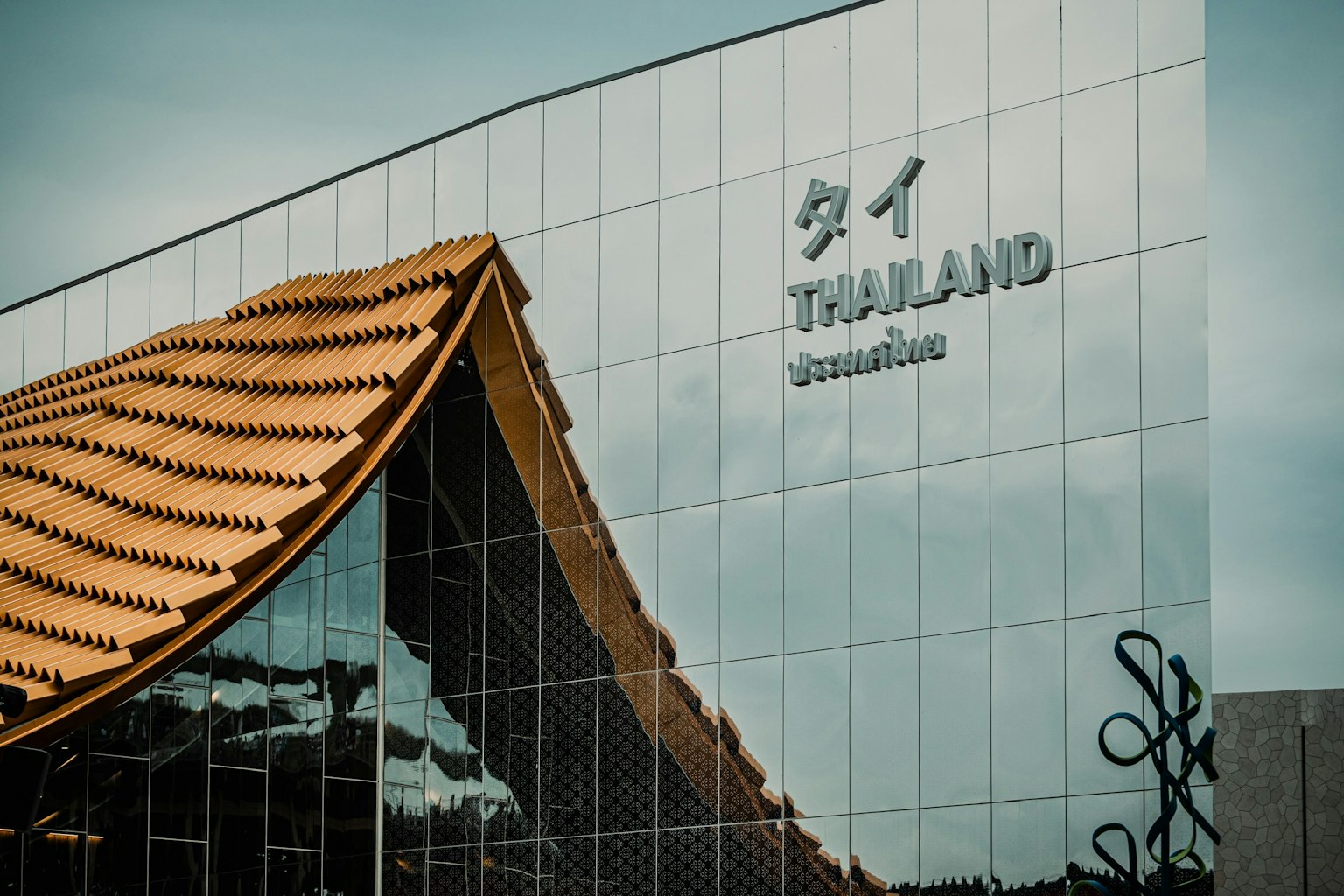 タイの現代的な建物の外観 鏡のようなガラスと伝統的な屋根のデザイン