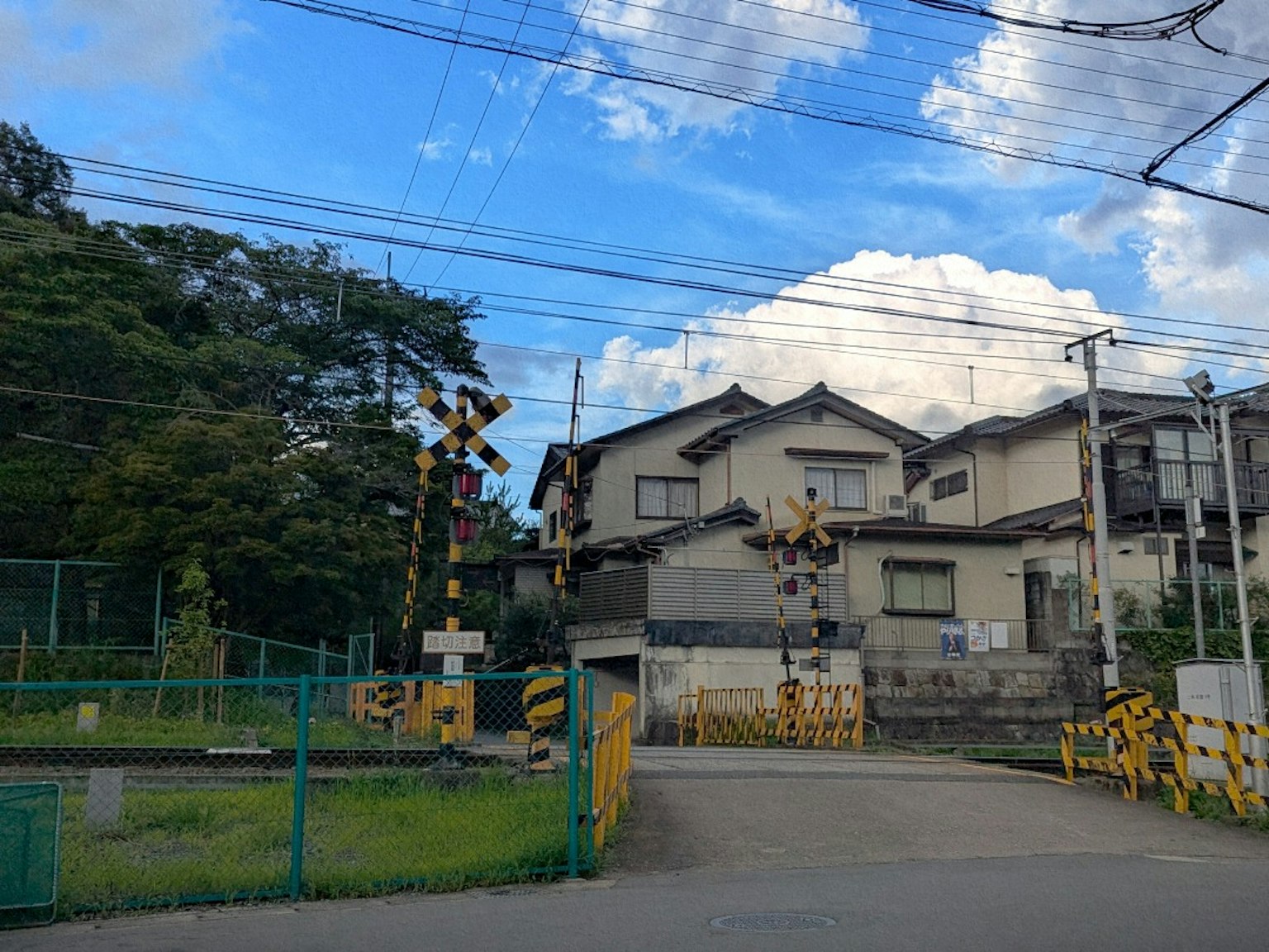 Railroad crossing with houses under a blue sky