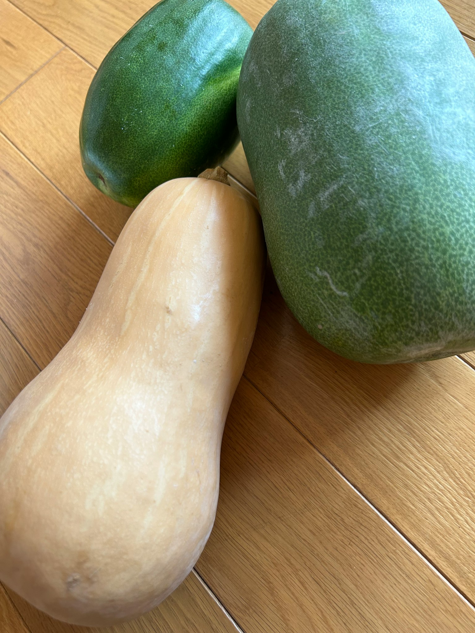 Zucca verde e zucca color crema posate su un pavimento in legno