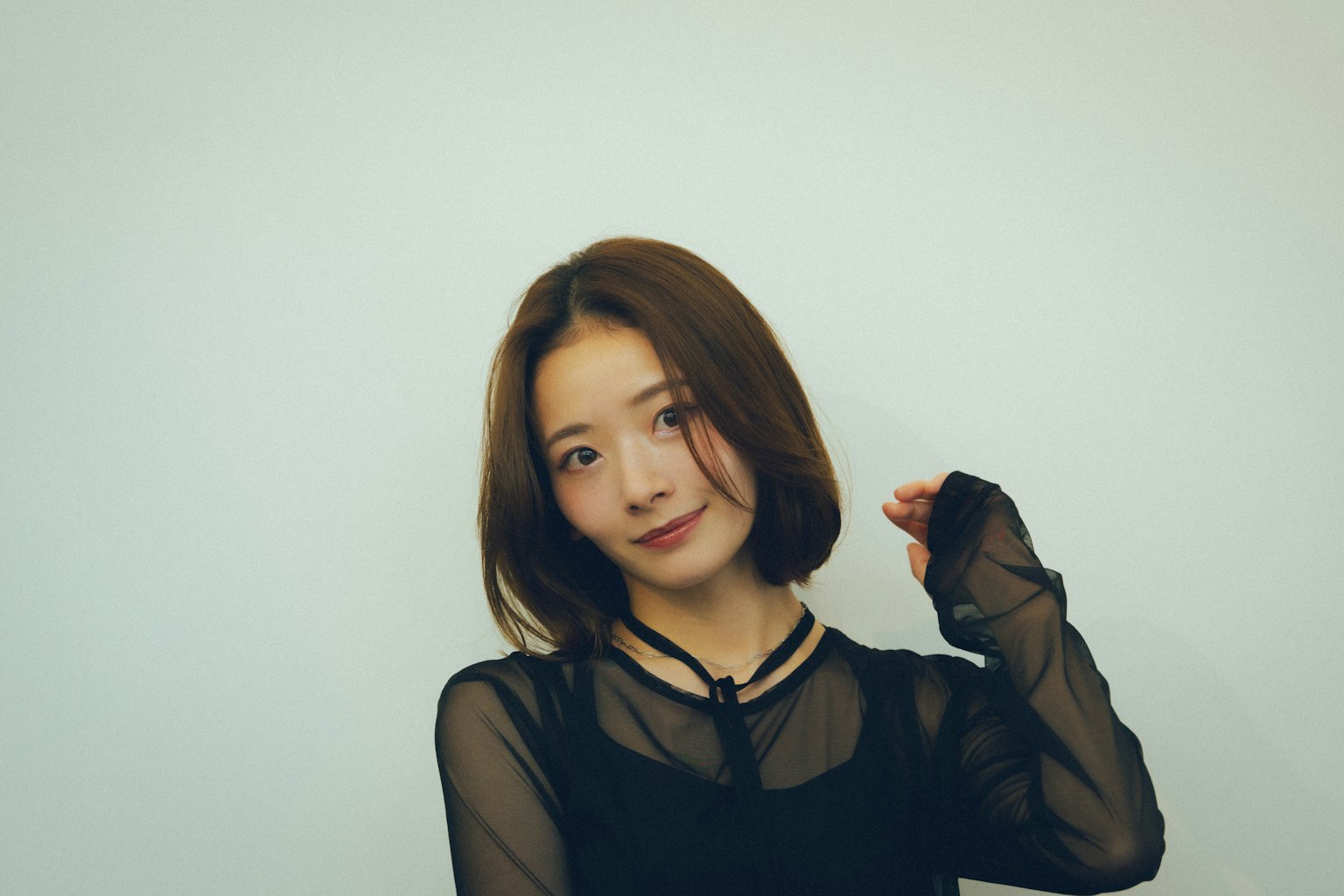 여성이 밝은 배경 앞에서 검은색 상의를 입고 미소 지으며 포즈를 취하고 있다