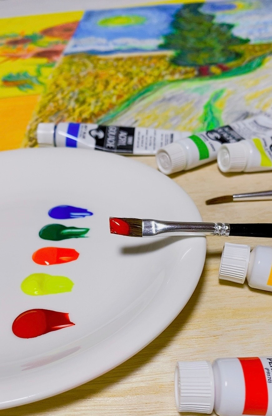 絵の具と筆が並ぶパレットのある制作机