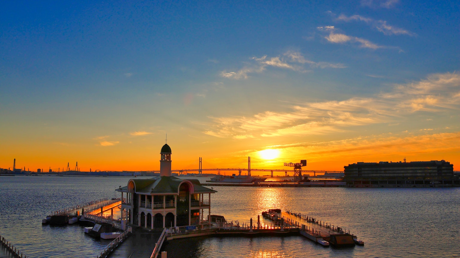 Vista escénica de un edificio sobre el agua con un muelle durante un hermoso atardecer