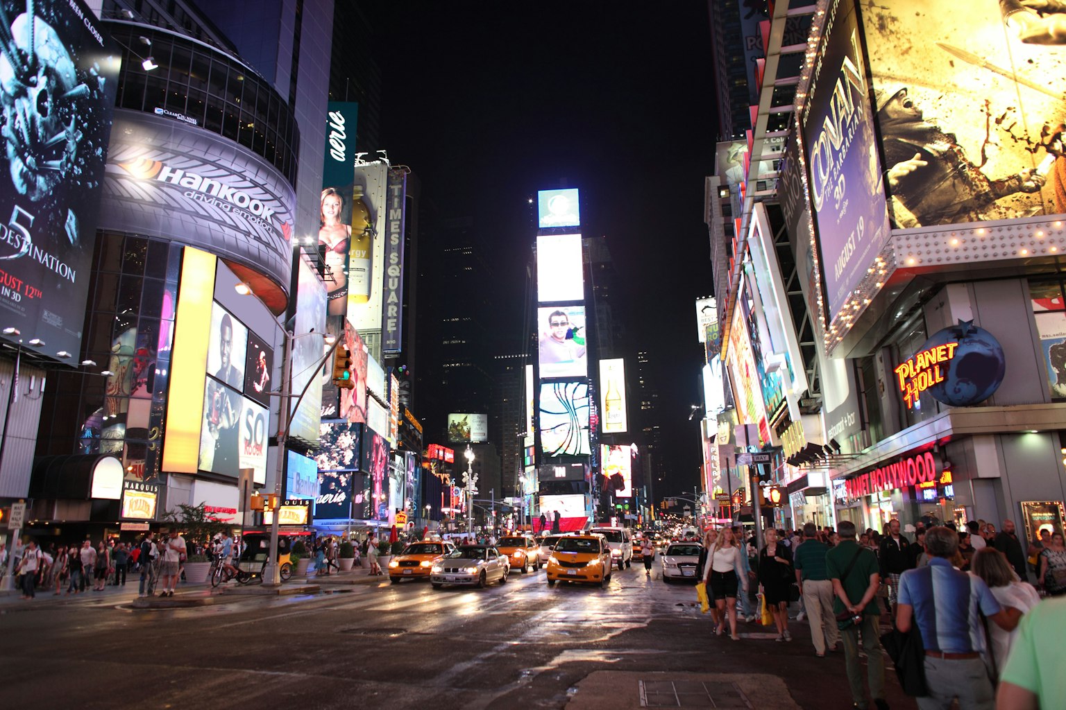 Busy street in Times Square at night with taxis and crowds