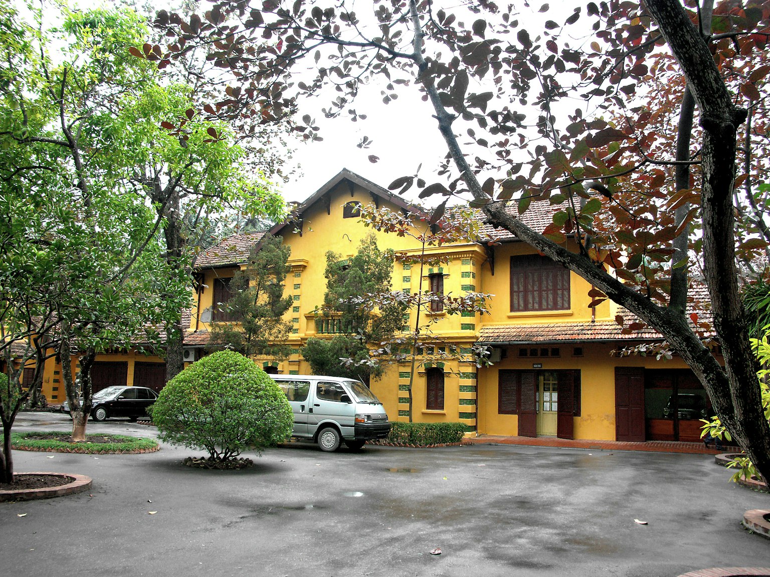 Edificio giallo circondato da alberi verdi e veicoli parcheggiati