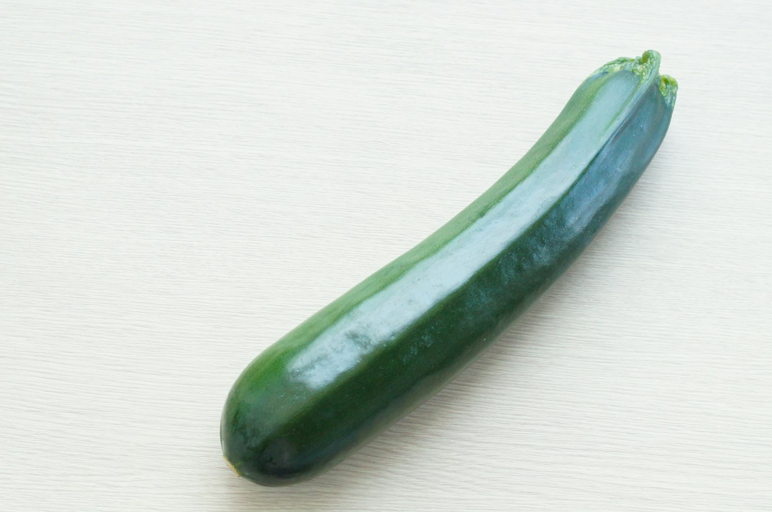 Un zucchino verde posato su uno sfondo bianco