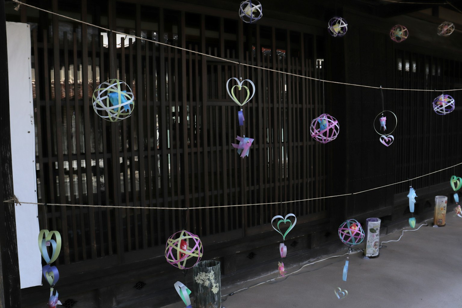 Adornos en forma de corazón coloridos colgando frente a una pared de listones de madera