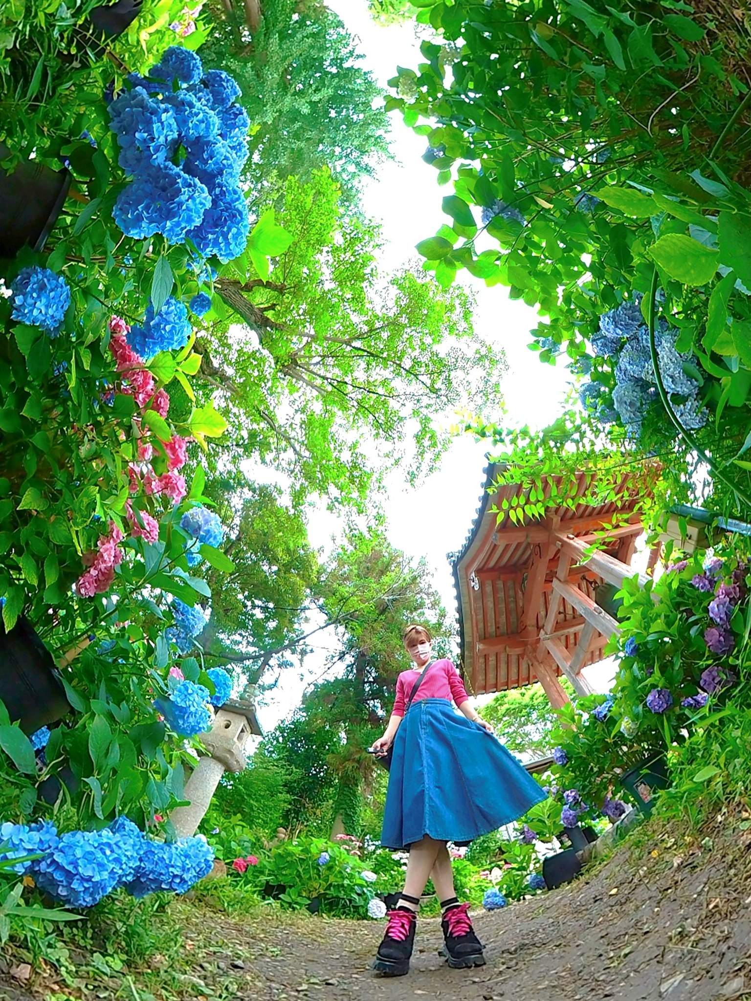 Fille en jupe bleue marchant sur un chemin bordé de fleurs