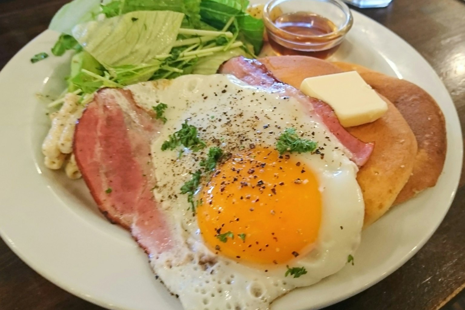 盘子上有煎蛋、火腿、沙拉和黄油