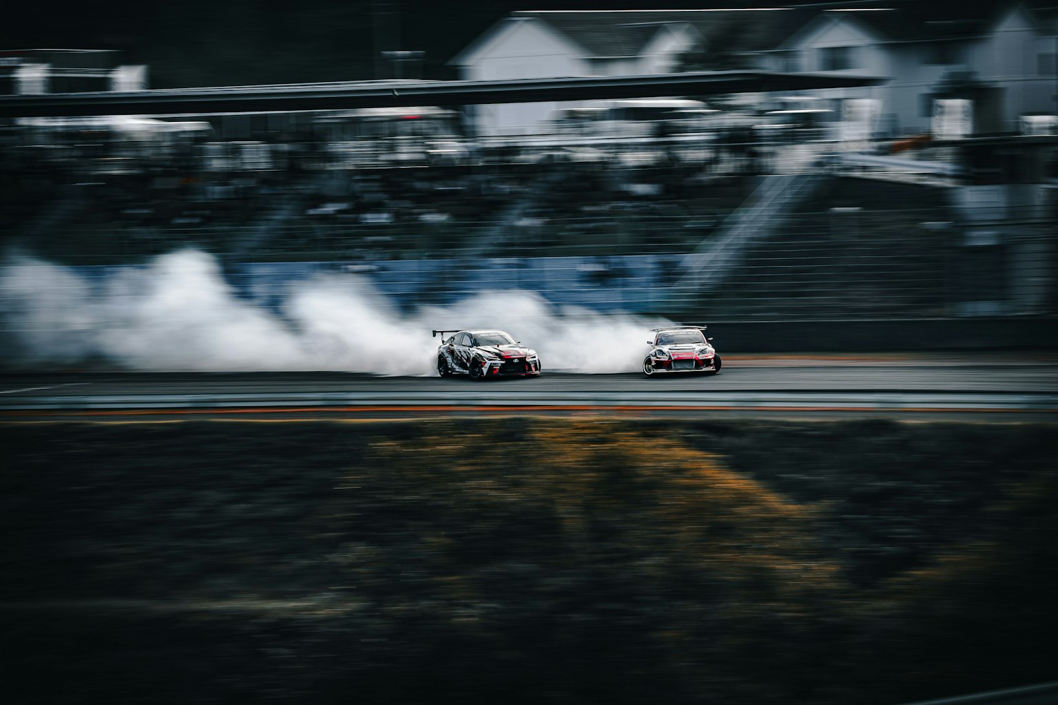 Zwei Autos driften auf einer Rennstrecke mit Rauch