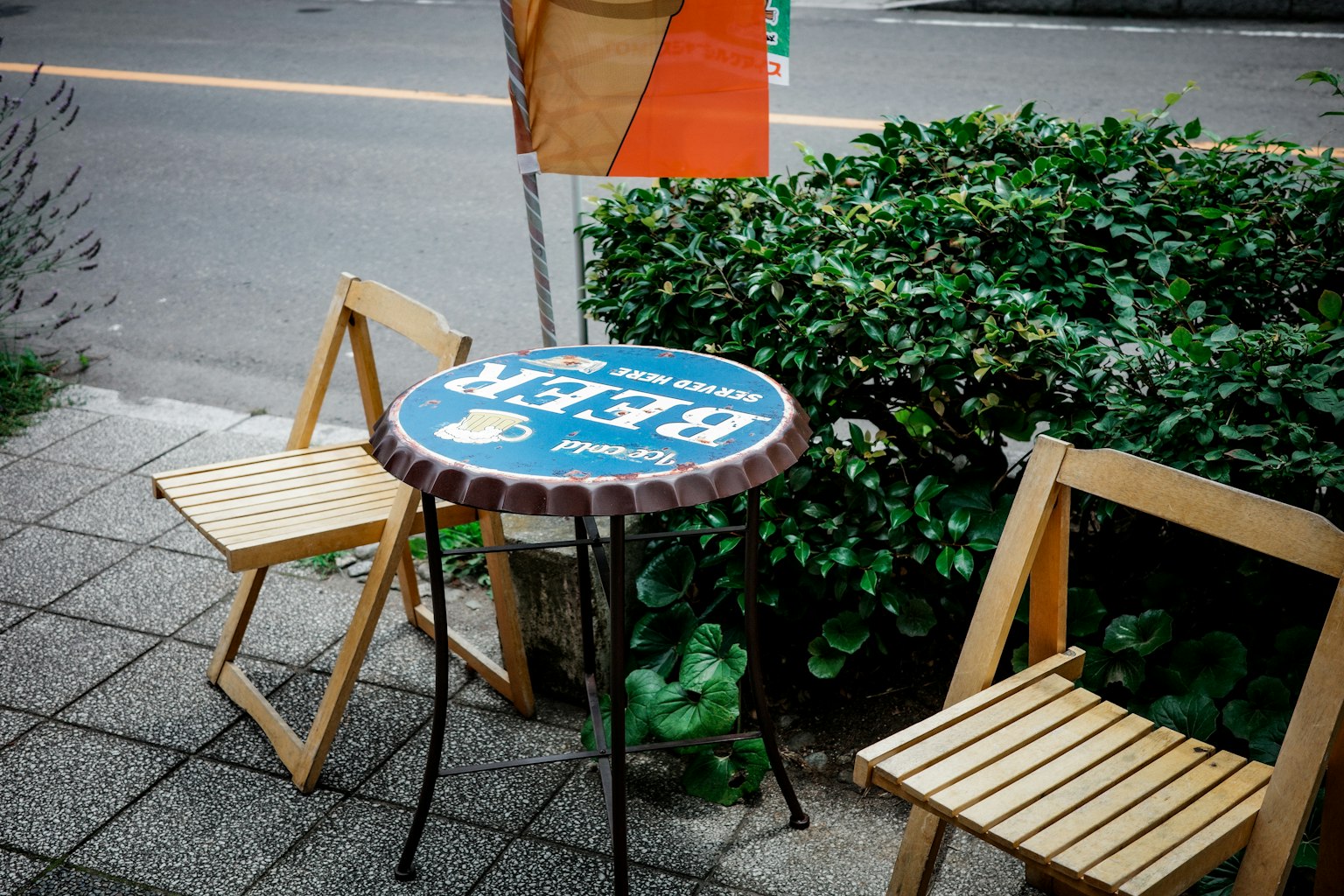 Un tavolo da caffè con piano blu rotondo e due sedie in legno in un ambiente esterno informale