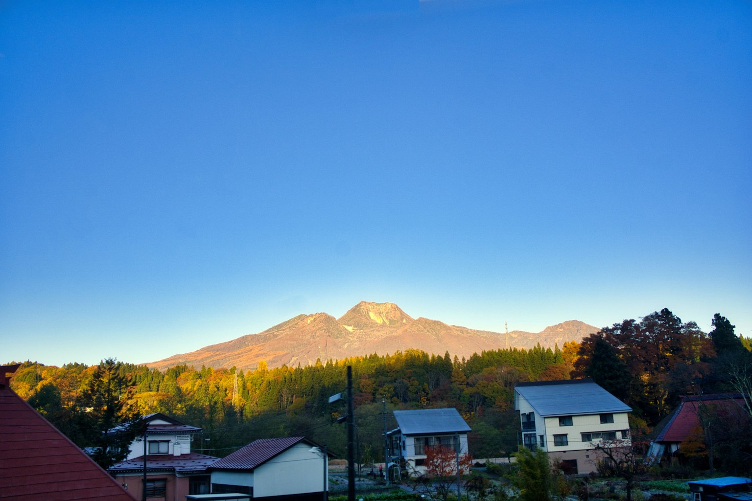 Serene village landscape with blue sky and mountains in the background