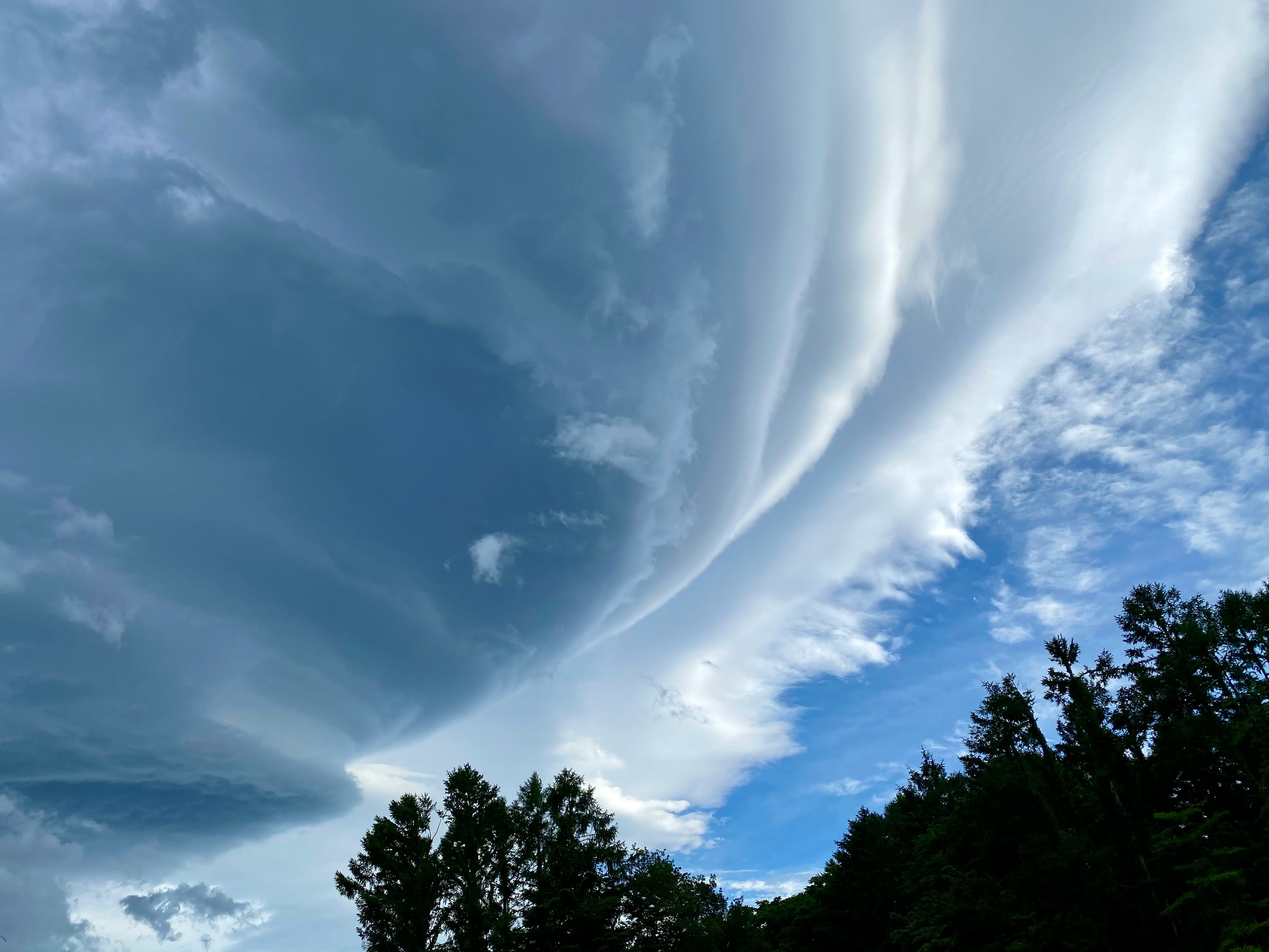 cielo blu con nuvole vorticosi sopra un paesaggio estivo