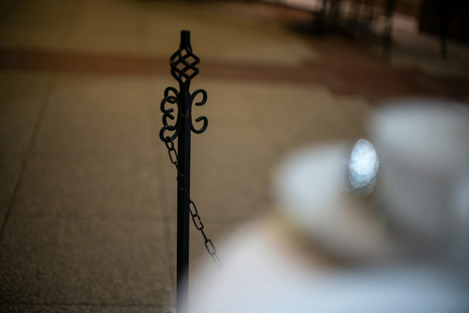 Black metal pole with chain and blurred cup and saucer in the background