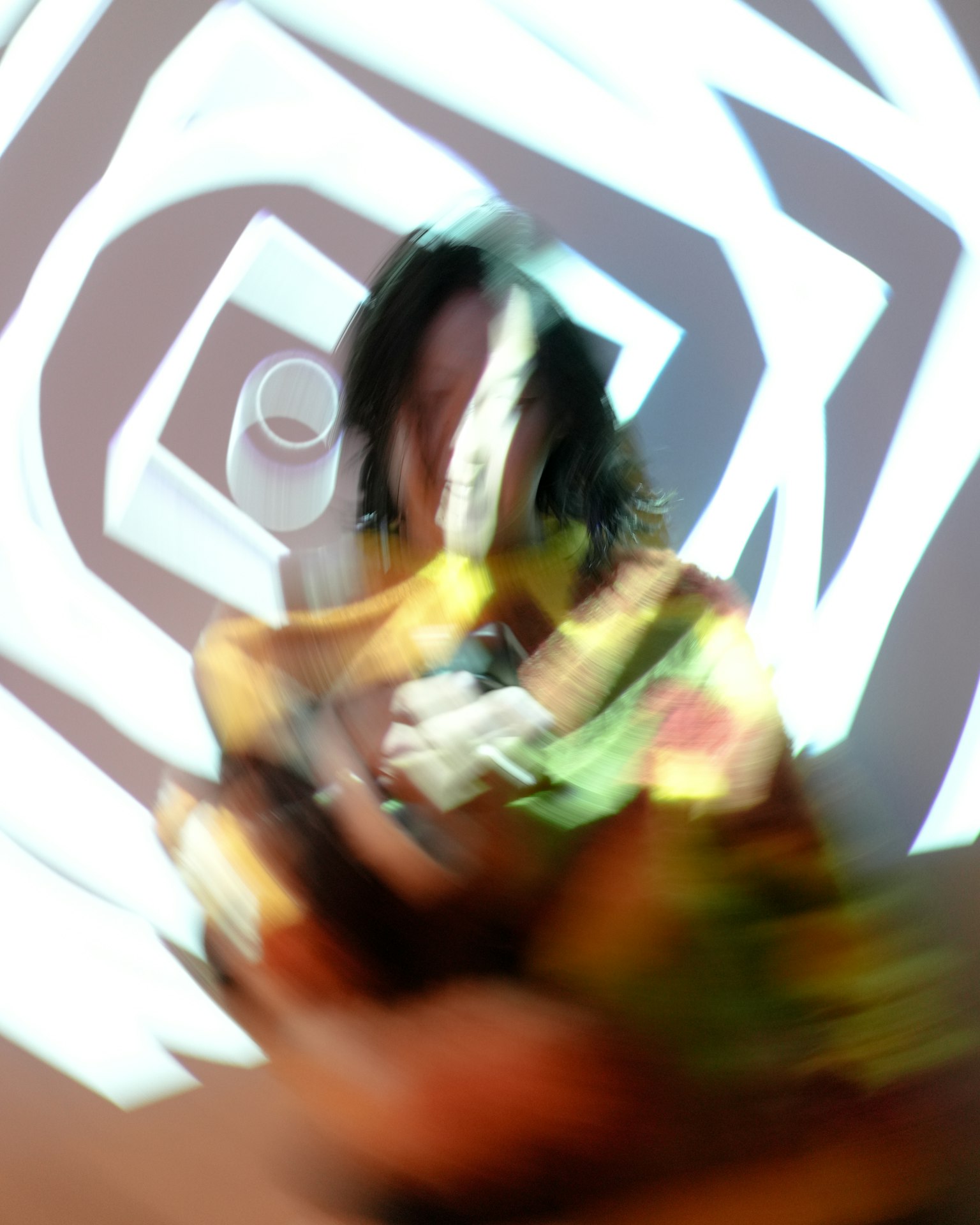 Blurred figure holding a colorful object with geometric projection in the background