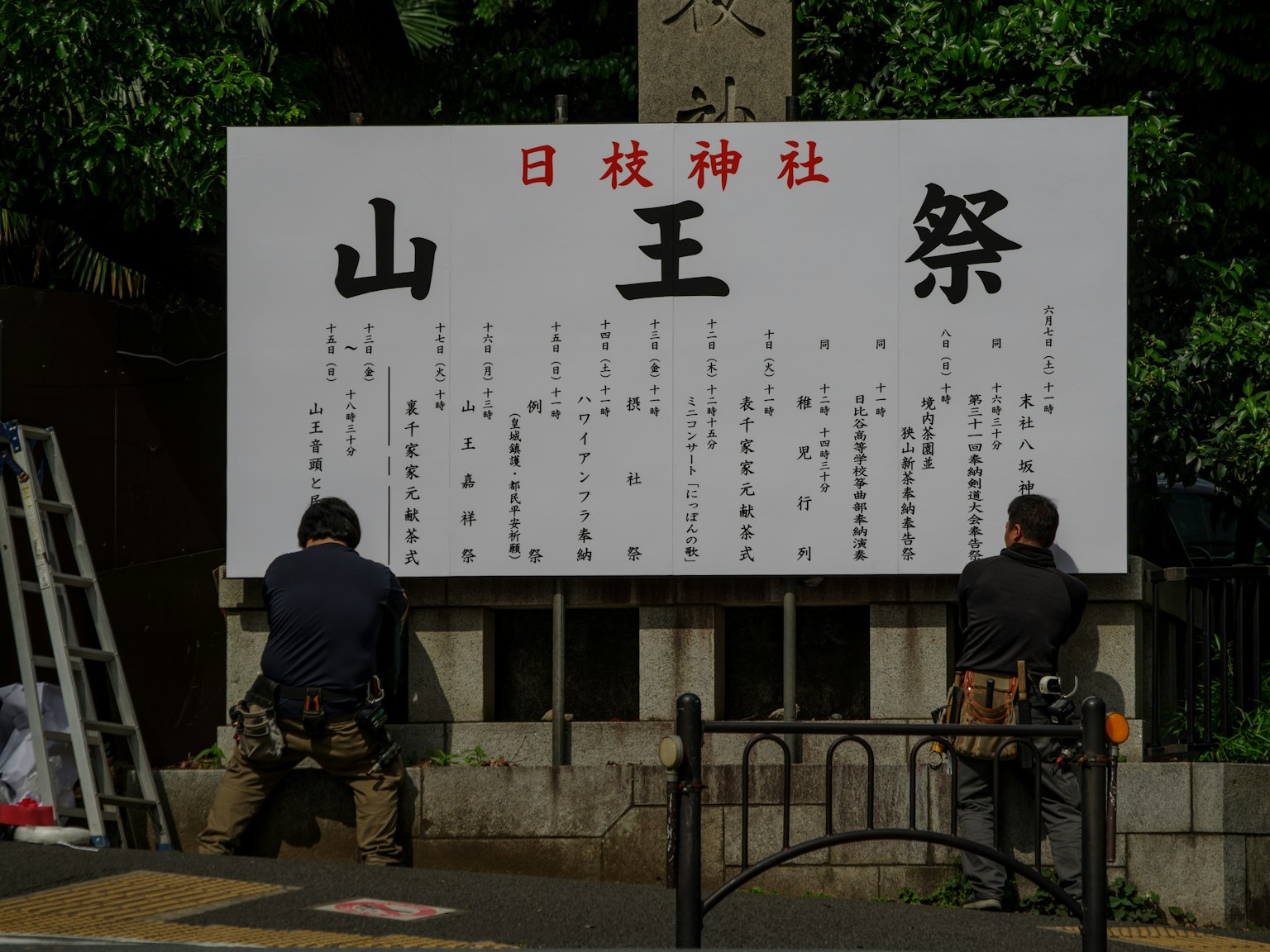 Deux travailleurs installant un panneau pour le festival Sanno Matsuri