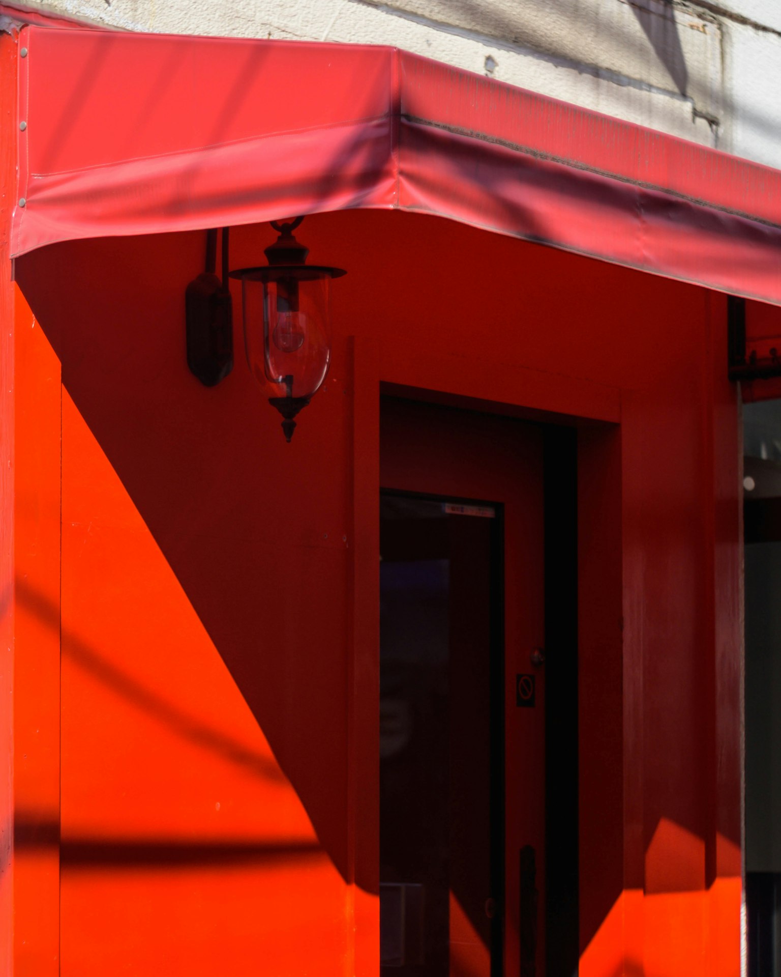 Extérieur rouge vif avec une porte simple et une lanterne sur le côté