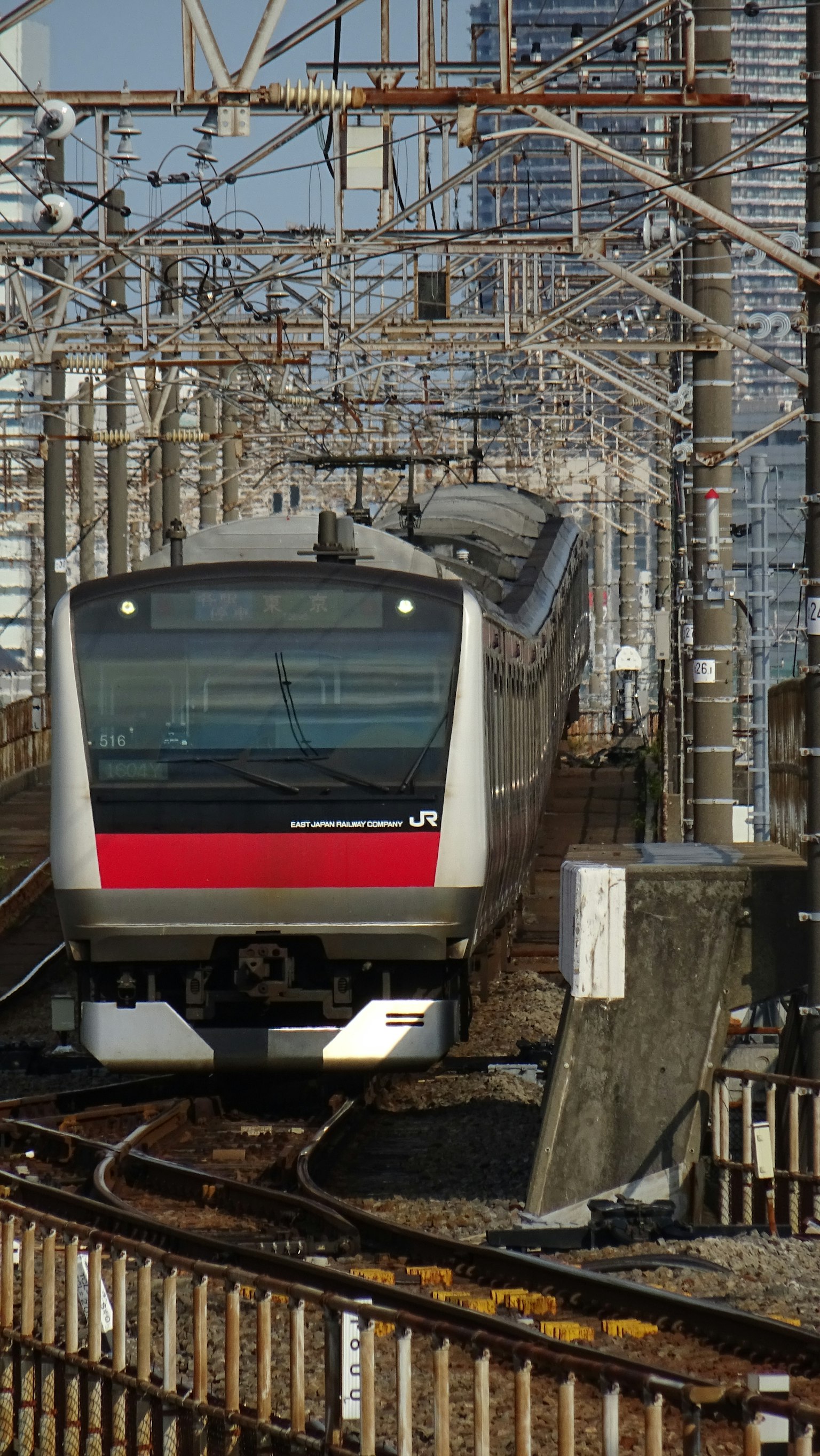 Ein moderner japanischer Zug mit einem roten Streifen, der auf den Gleisen fährt