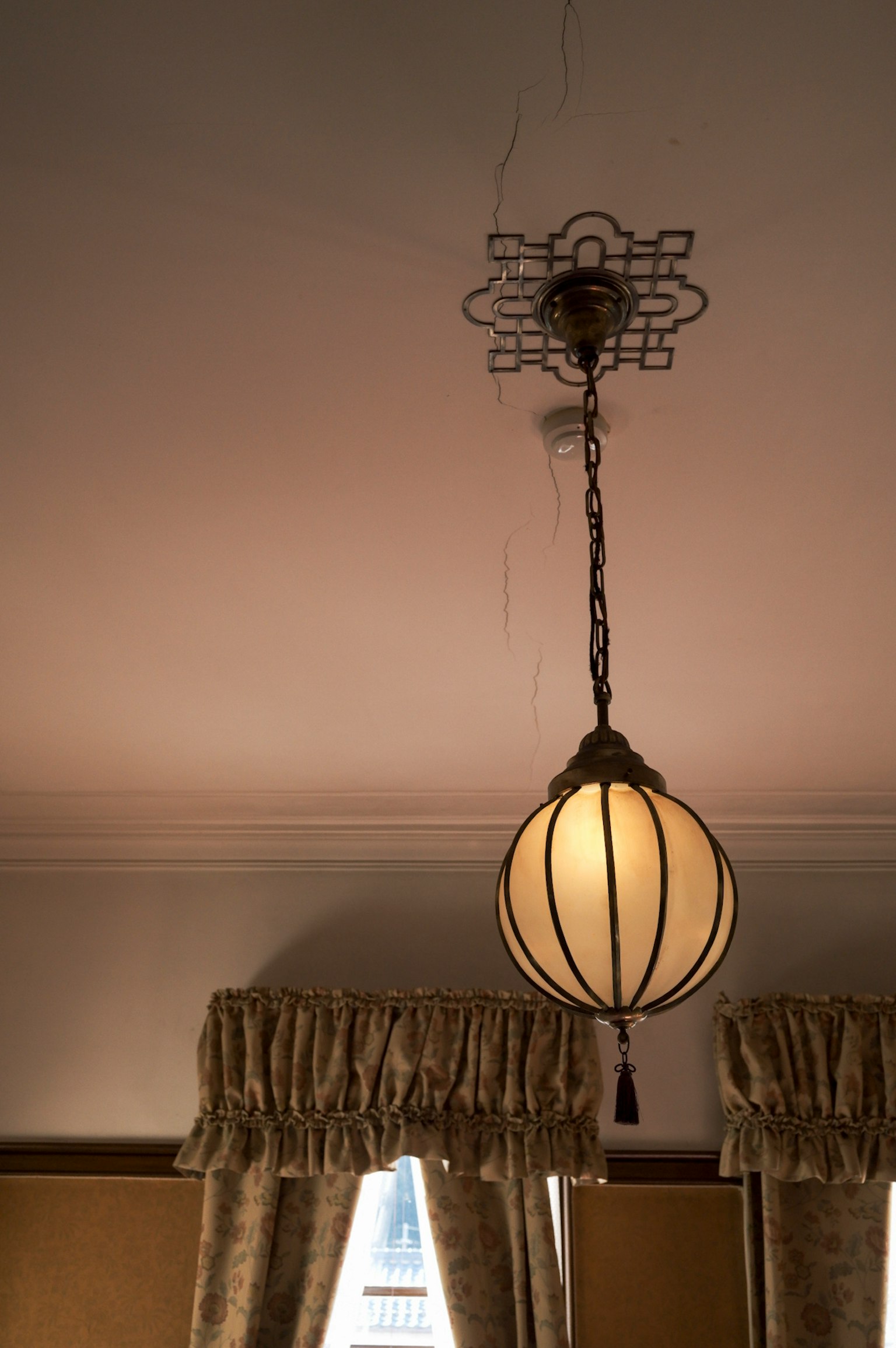 Belle lampe suspendue au plafond avec des rideaux élégants en arrière-plan