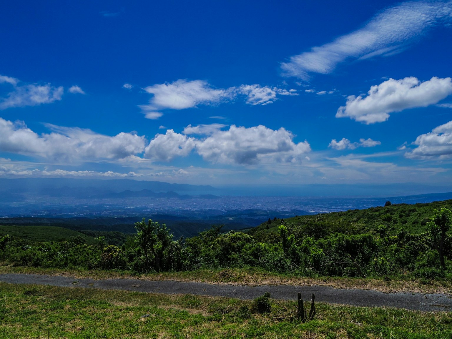 Lanskap luas dengan langit biru dan awan putih bukit hijau dan jalan berliku