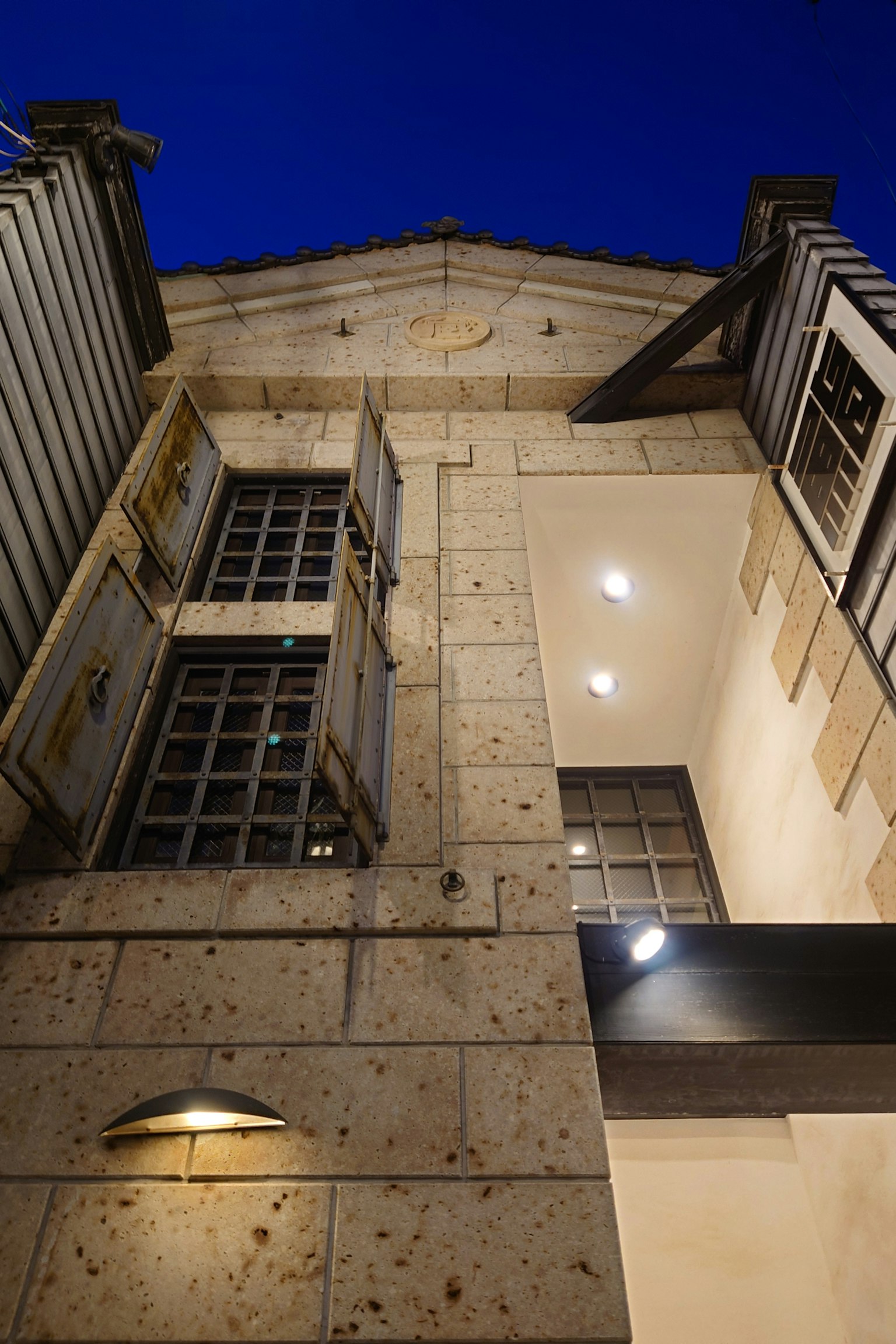 Façade en pierre d'un bâtiment avec des fenêtres ouvertes sous le ciel nocturne