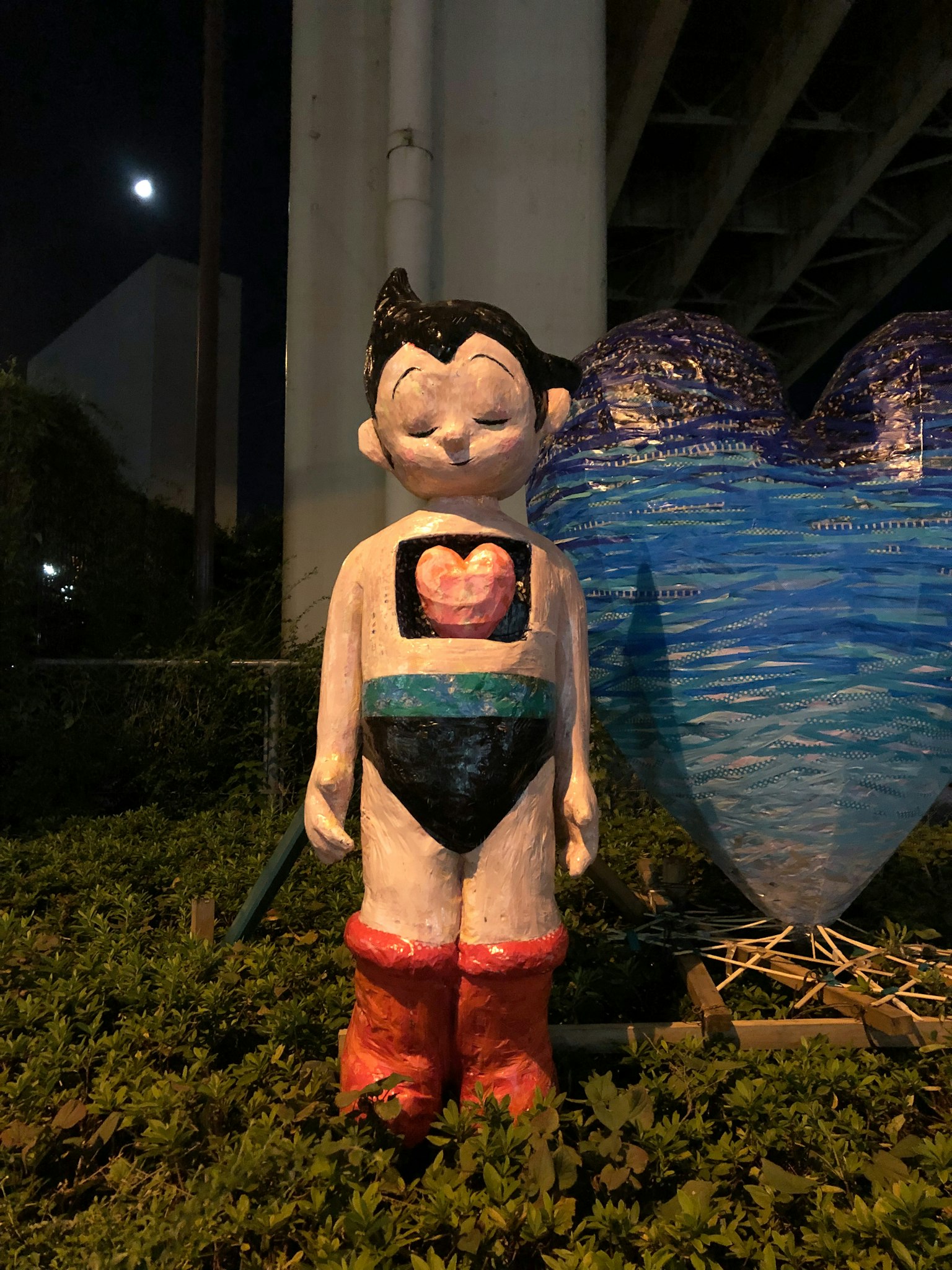 Estatua colorida de un personaje de pie en un parque por la noche