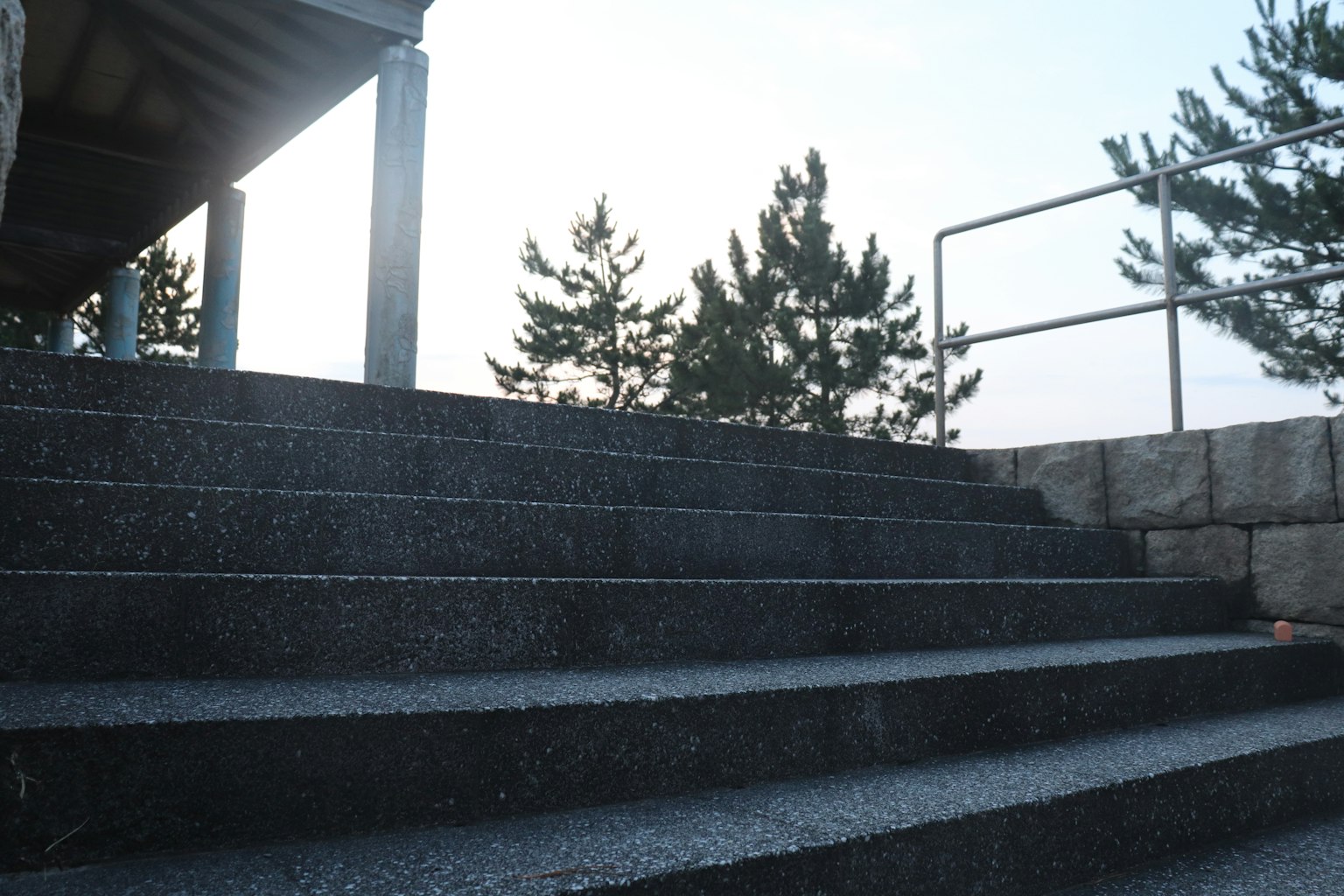 Treppe nach oben mit Geländer und silhouettierten Bäumen