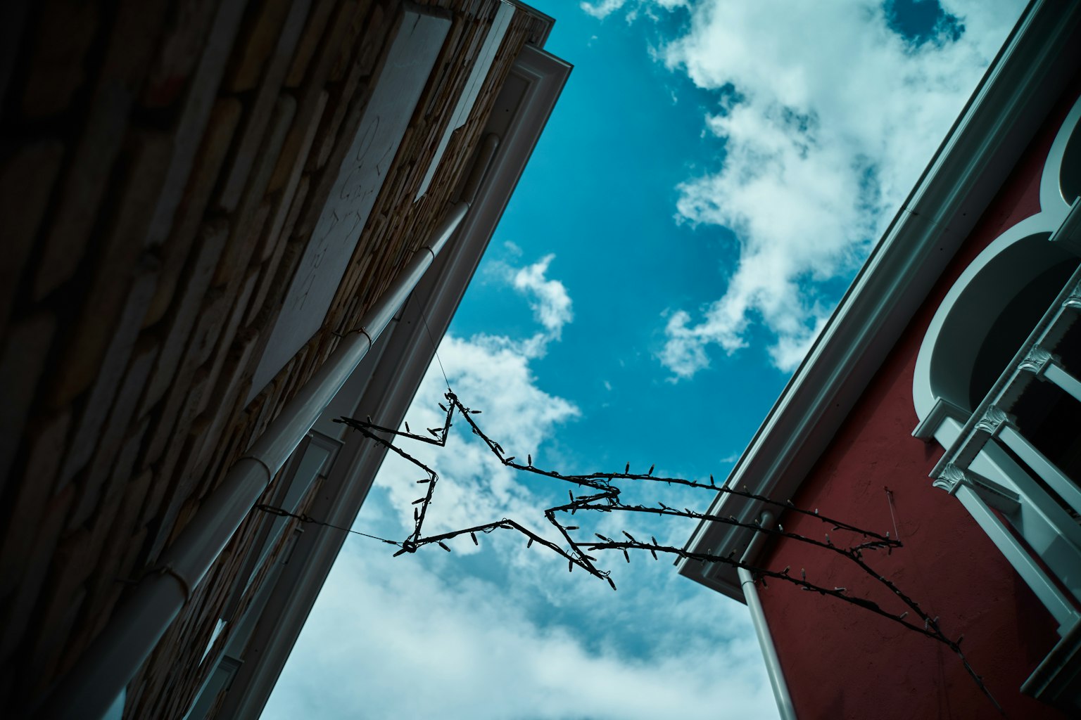 Vista di una decorazione a forma di stella sotto un cielo blu tra gli edifici