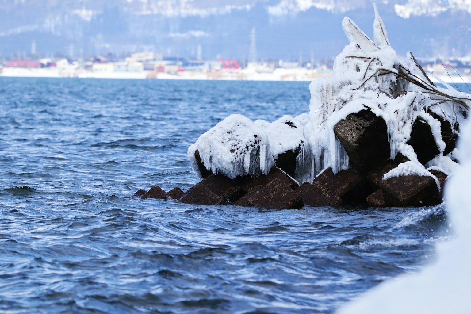 Frozen rocks covered with snow by the water's edge
