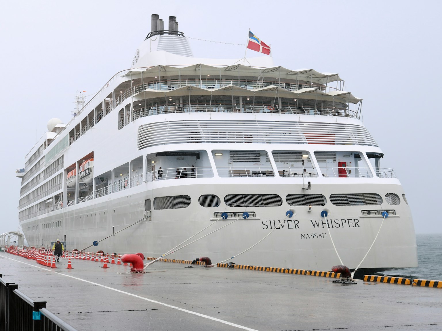 Una grande nave da crociera bianca ormeggiata sotto la pioggia