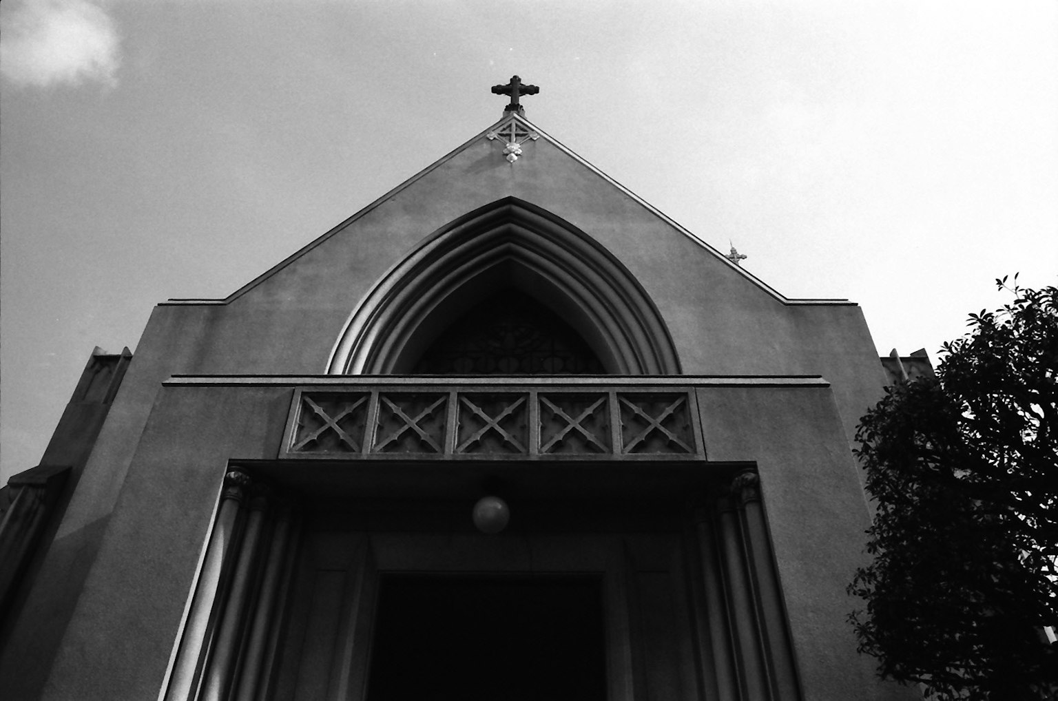 Photo de la façade d'une église avec une croix et des fenêtres en arc pointu