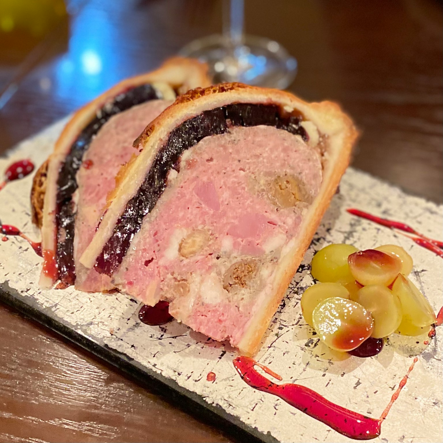 Tranches de pâté servies sur une assiette décorative avec garniture de fruits