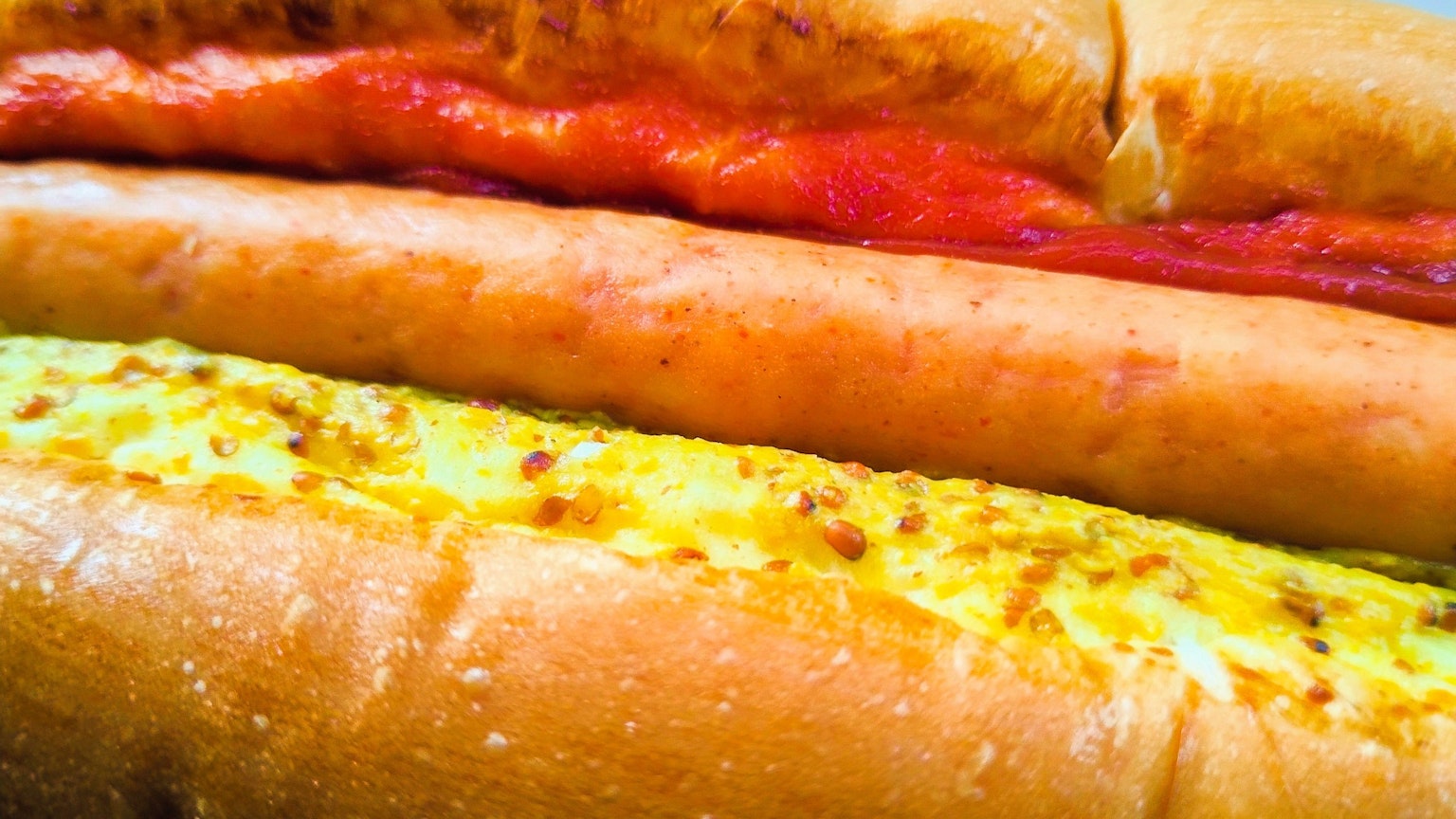Tre panini hot dog impilati con diverse salse