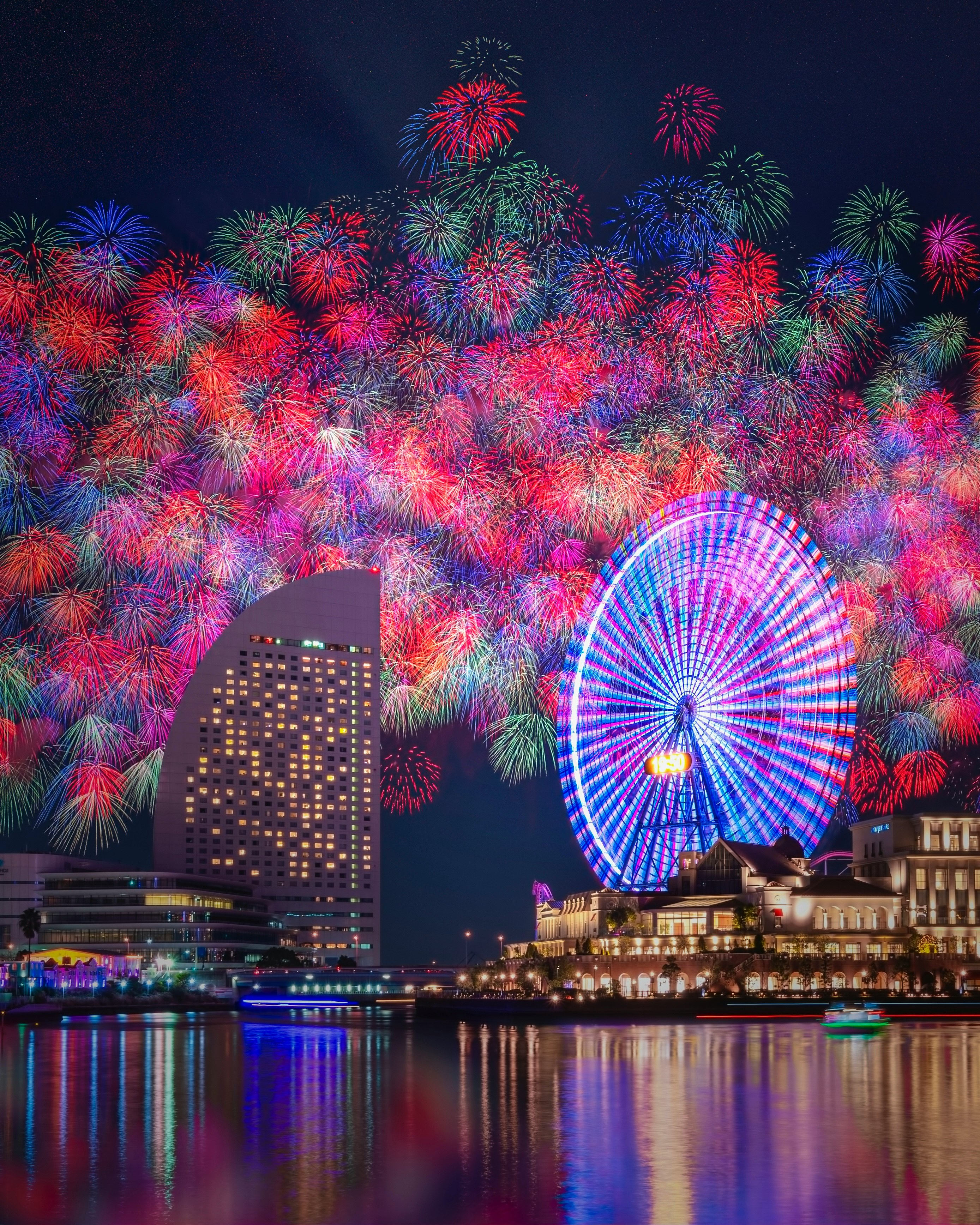 colorful fireworks and Ferris wheel illumination along a riverside at night
