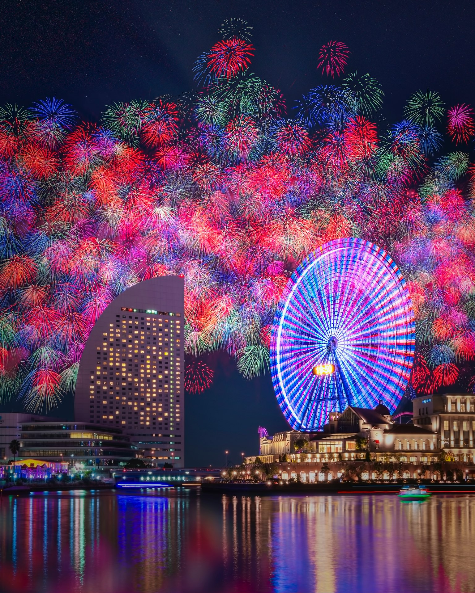 Fuochi d'artificio colorati che illuminano il cielo notturno sopra una città con una ruota panoramica