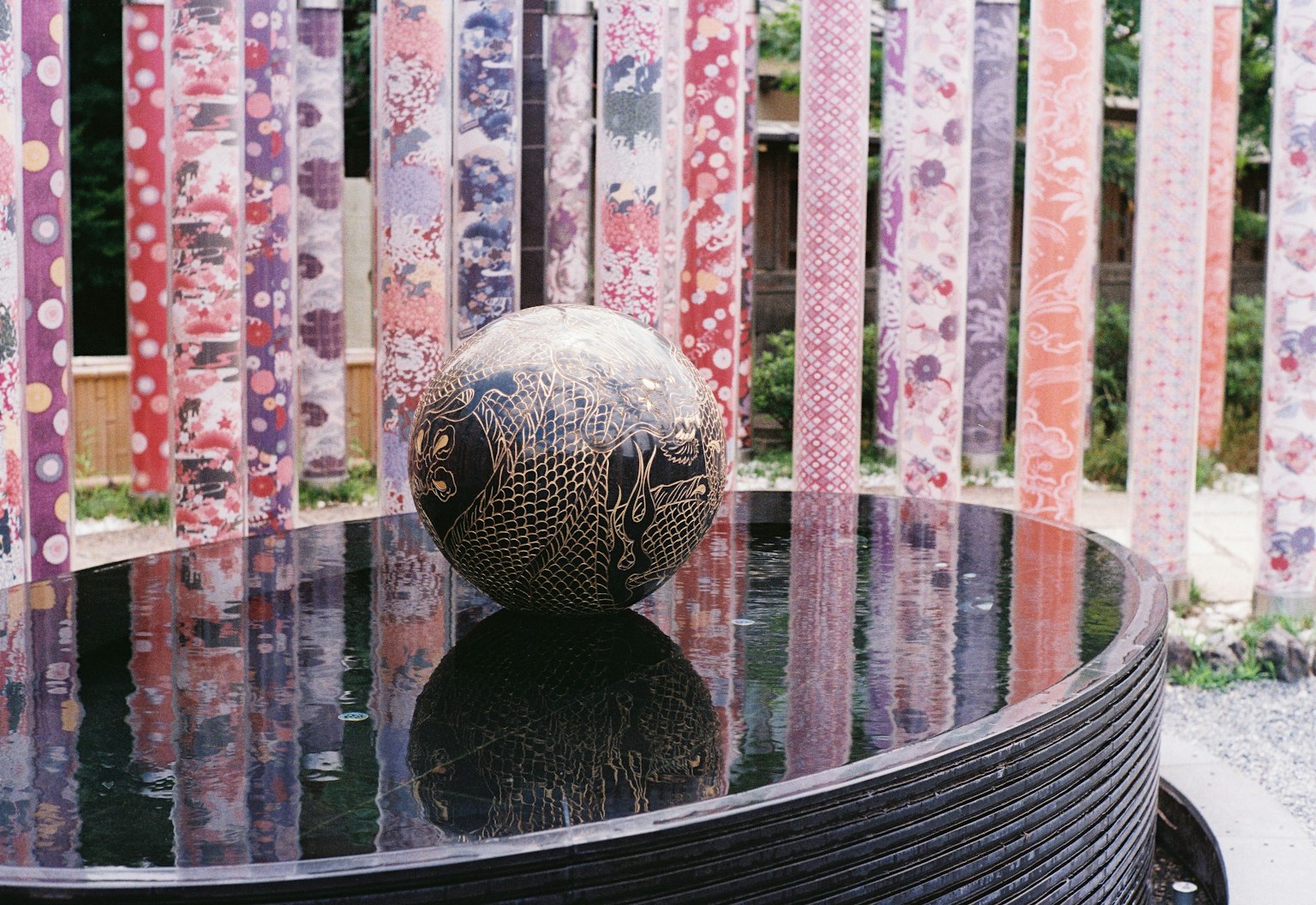 Eine schön gemusterte Keramikkugel auf einem schwarzen Tisch mit buntem Stoffhintergrund