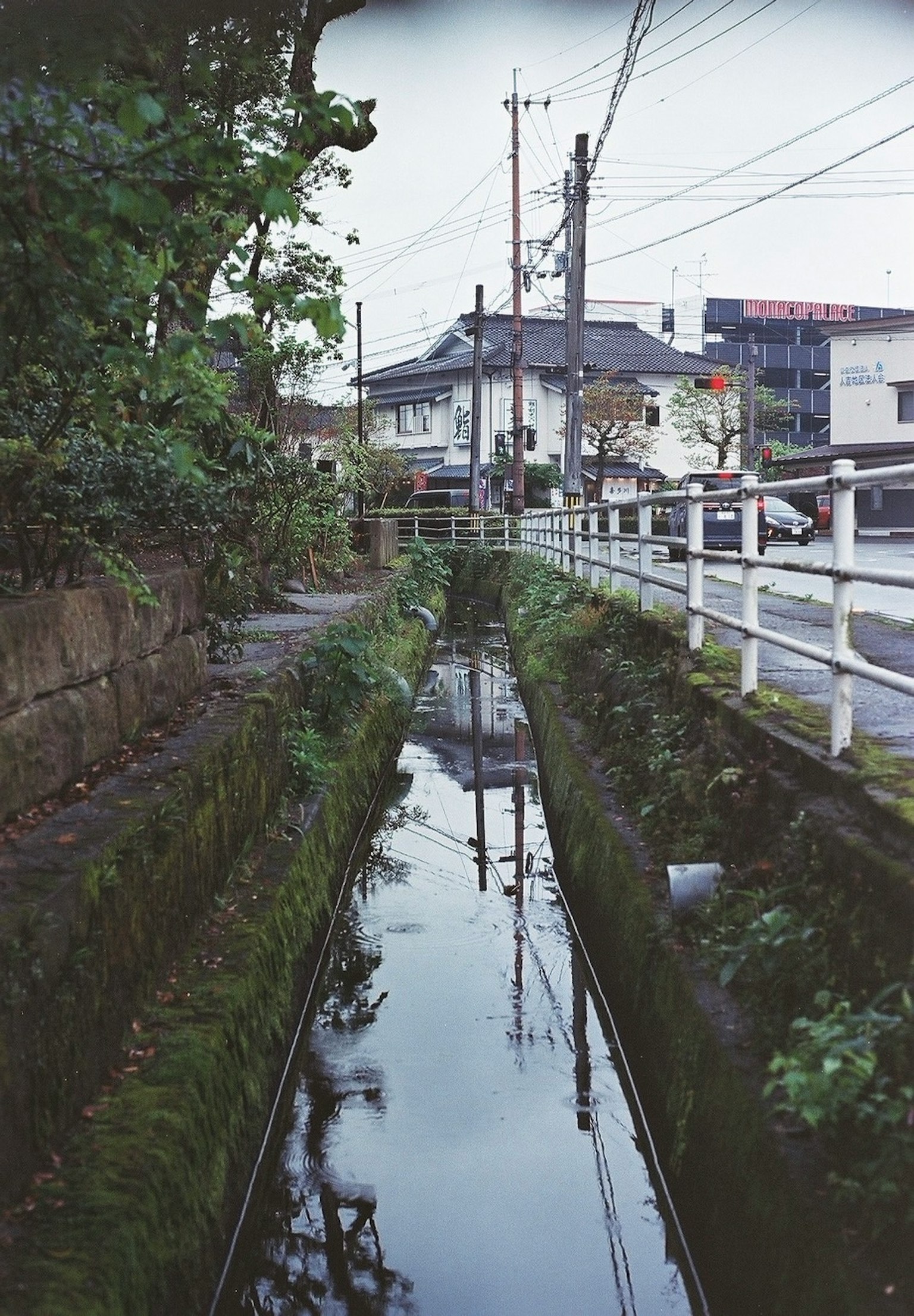 Schmaler Wasserweg, der umliegende Häuser und Bäume reflektiert