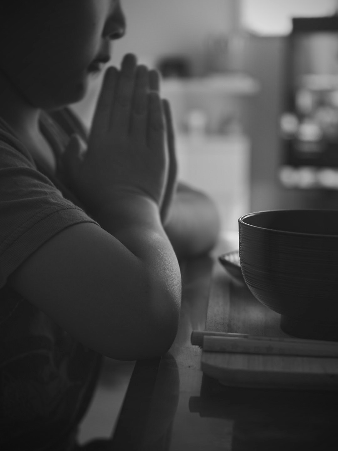 手を合わせてあいさつする人物と湯呑みのある室内