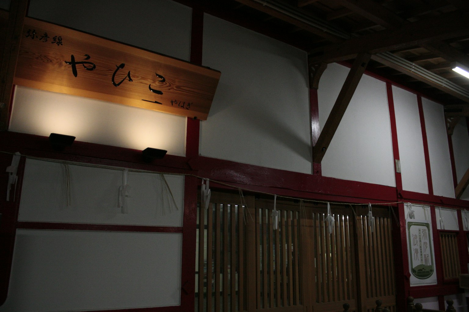 Innenraum mit rot gerahmten Wänden und einem Holzschild mit japanischen Zeichen
