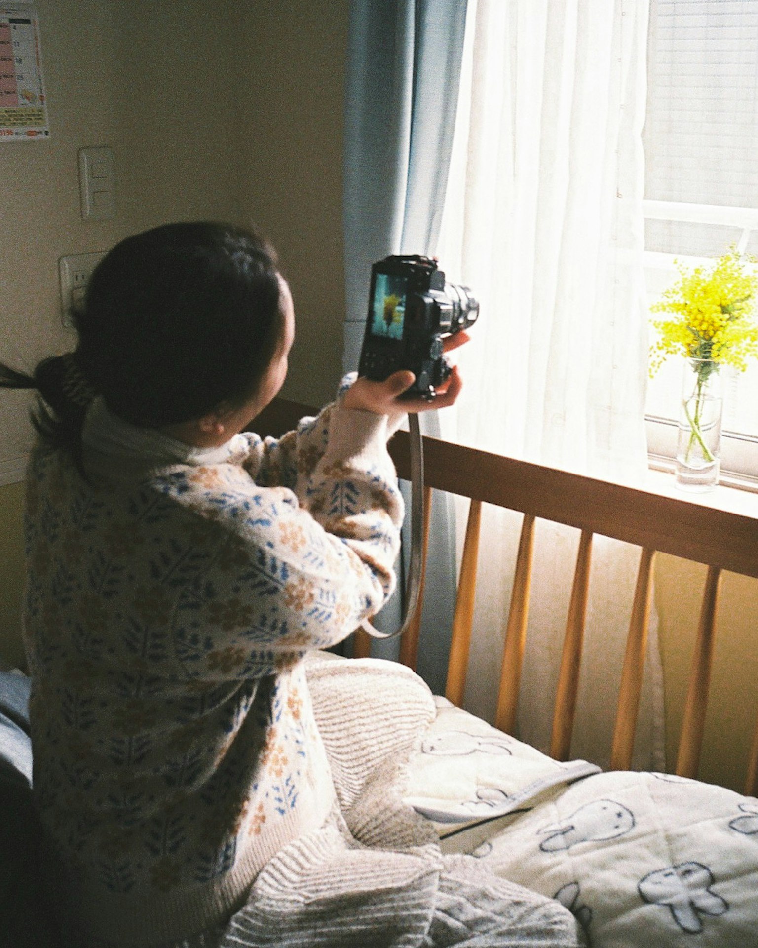 Gadis yang mengambil foto bunga di dekat jendela