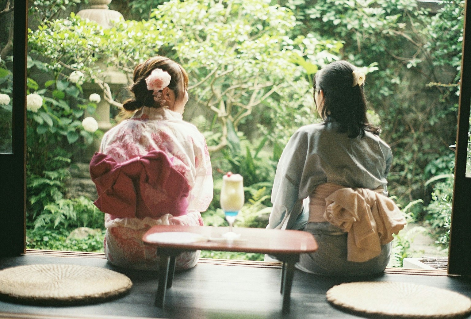 Due donne in kimono sedute e che guardano un giardino