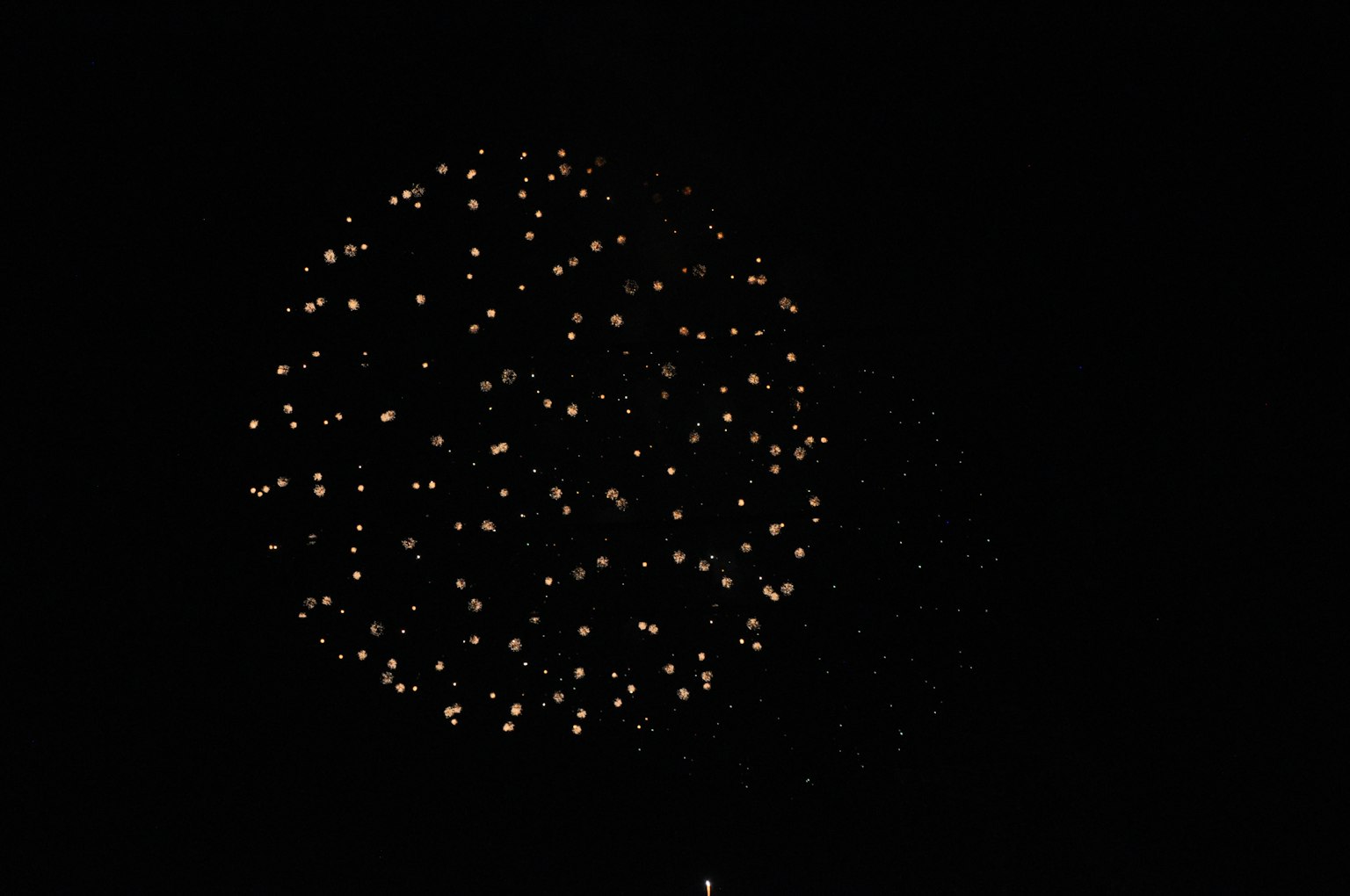 Fuochi d'artificio dorati che esplodono nel cielo notturno con uno sfondo scuro