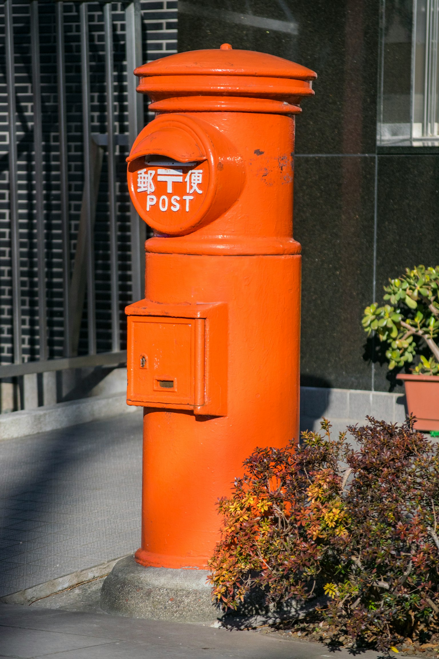 Orange postal mailbox with a small letter slot in a modern setting