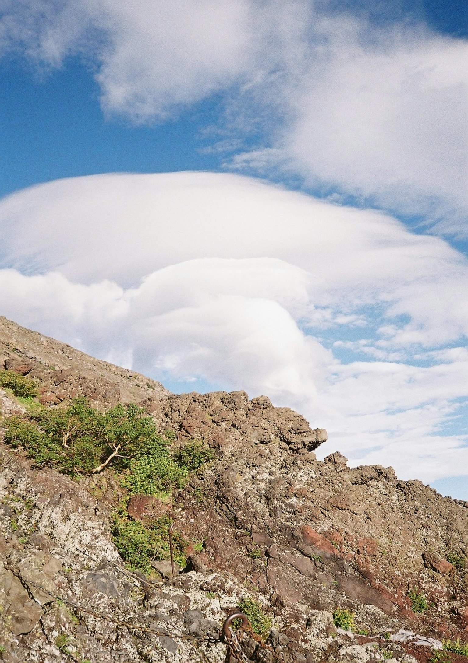Lenticular clouds above rocky terrain with blue sky