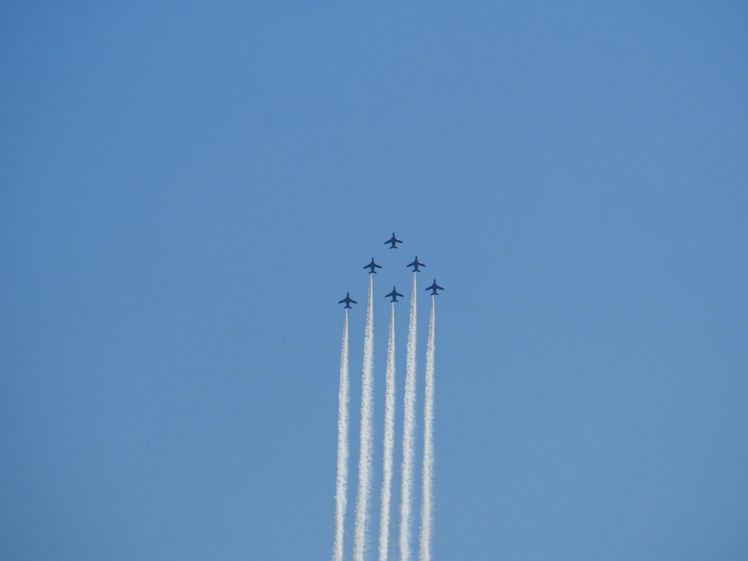 Formación de aviones ascendiendo en un cielo azul