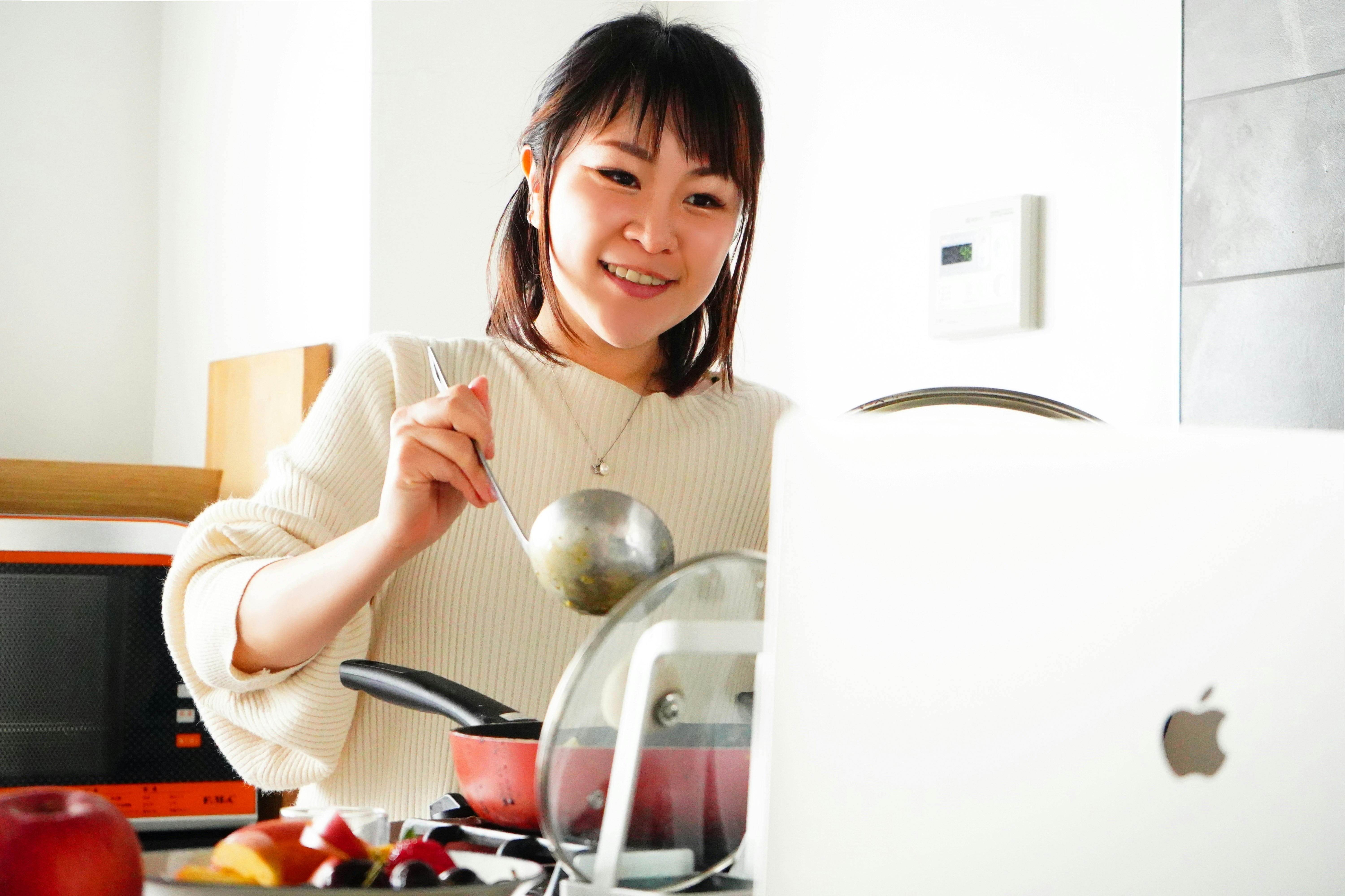 femme souriante tenant une casserole dans une cuisine