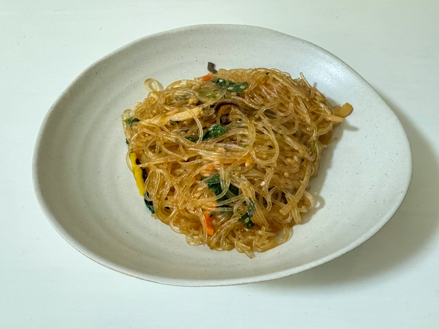 Salad mie kaca gaya Korea disajikan di atas piring putih