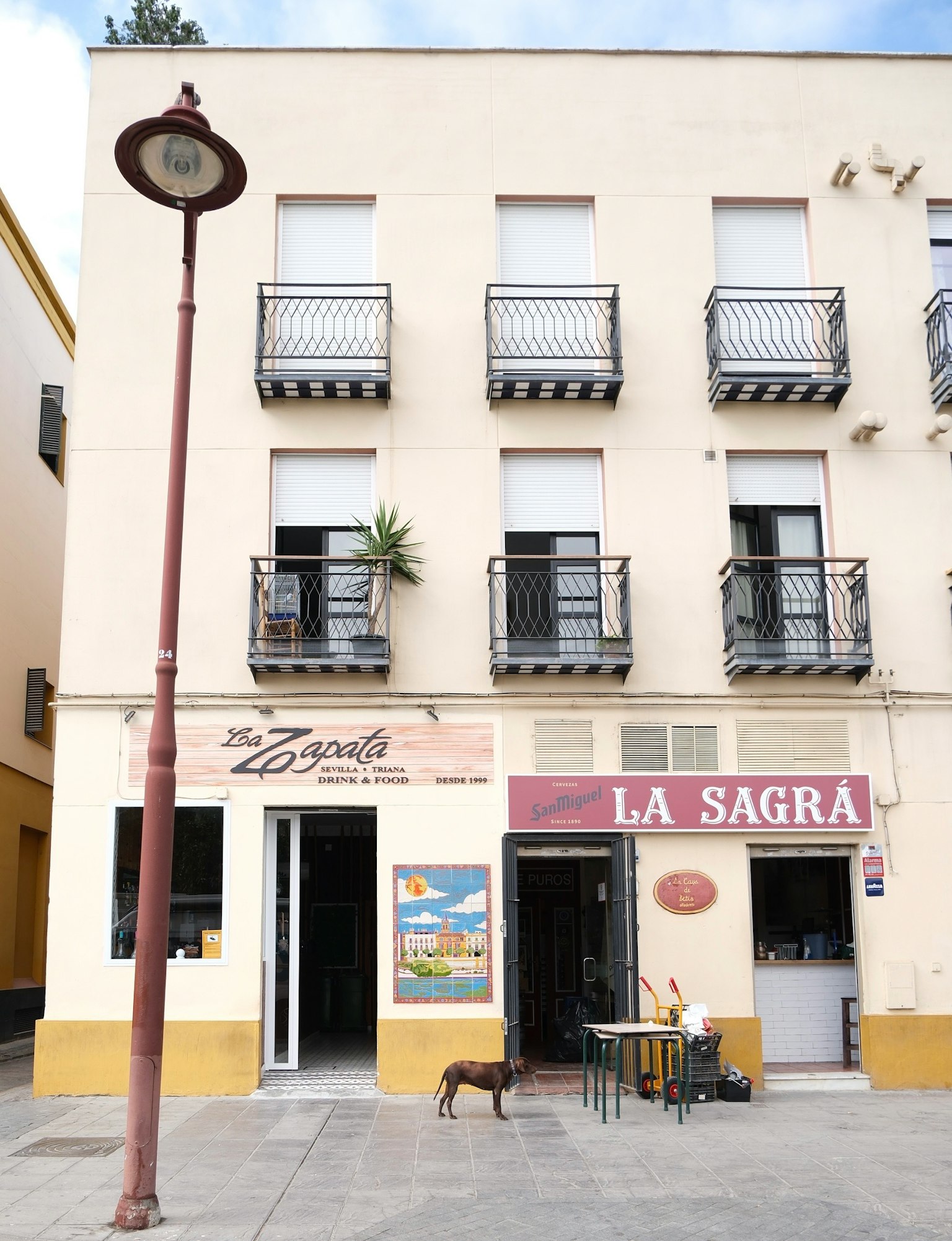 Un edificio con pareti bianche e balconi, con un caffè chiamato 'LA SAGRA' sotto
